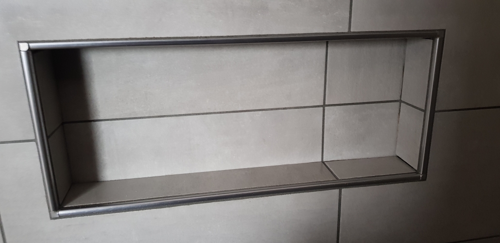 Flisearbejde med indbygget hylde i flisevæg på Salling