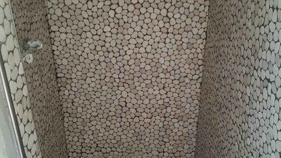 Flisearbejde med naturstensmosaik og bænk i bruseområde i Spøttrup