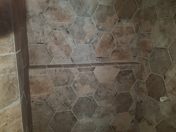 Flisearbejde i bruseniche med sekskantede fliser og hylde i Skive